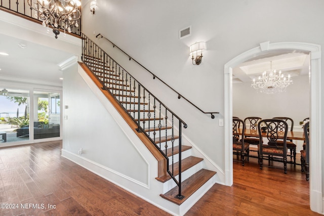 stairway with a notable chandelier, crown molding, and dark hardwood / wood-style floors