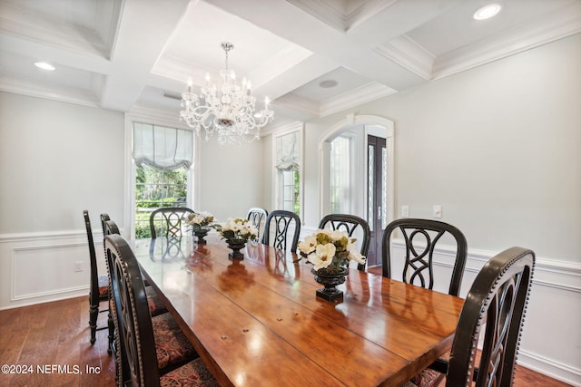 dining space with dark hardwood / wood-style flooring, an inviting chandelier, coffered ceiling, and crown molding