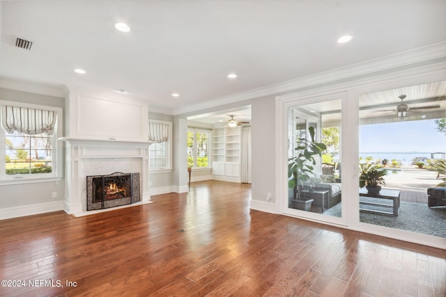 unfurnished living room with wood-type flooring, a fireplace, ceiling fan, and a healthy amount of sunlight