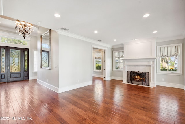 unfurnished living room with a wealth of natural light, a fireplace, dark hardwood / wood-style floors, and an inviting chandelier