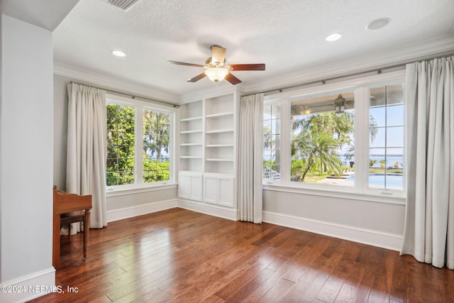 spare room featuring dark hardwood / wood-style floors, ceiling fan, built in shelves, and a textured ceiling