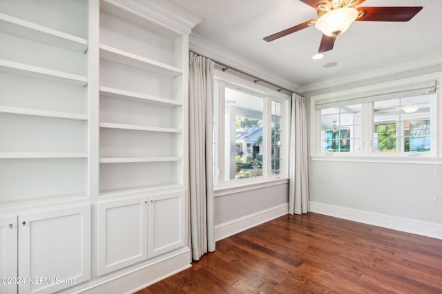 empty room with ornamental molding, dark hardwood / wood-style flooring, ceiling fan, and built in features