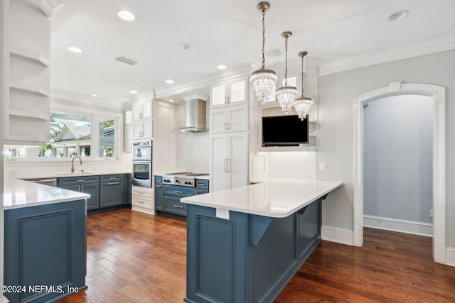 kitchen featuring blue cabinets, wall chimney exhaust hood, backsplash, decorative light fixtures, and dark hardwood / wood-style floors