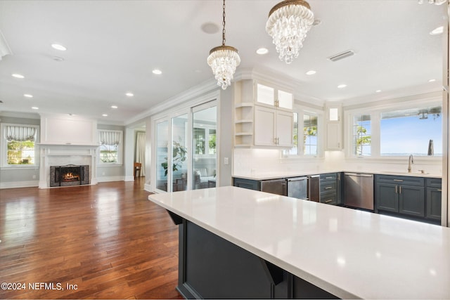 kitchen with white cabinets, dark wood-type flooring, a high end fireplace, crown molding, and pendant lighting