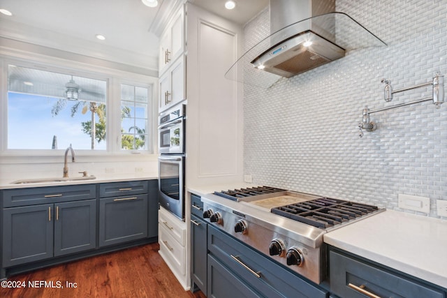 kitchen featuring white cabinets, sink, backsplash, and wall chimney range hood