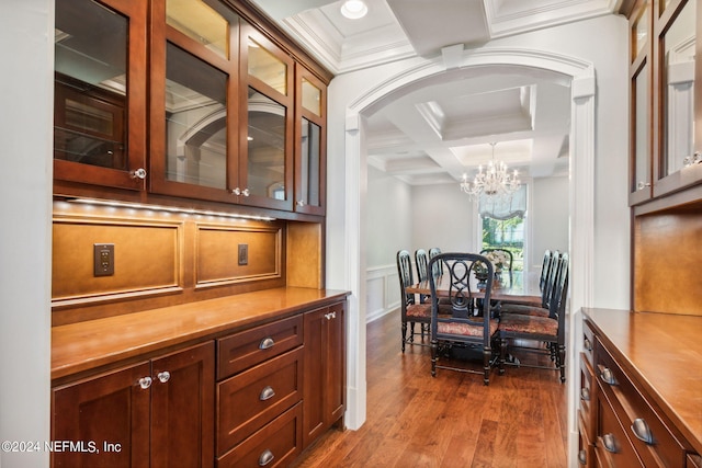 interior space featuring beamed ceiling, ornamental molding, an inviting chandelier, hardwood / wood-style flooring, and coffered ceiling