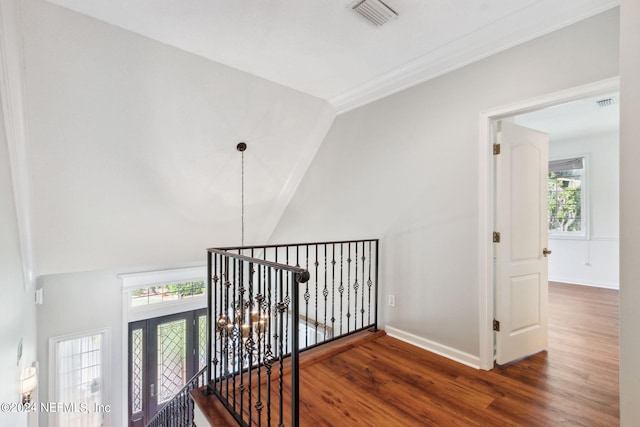 hallway featuring vaulted ceiling, dark hardwood / wood-style flooring, an inviting chandelier, and ornamental molding