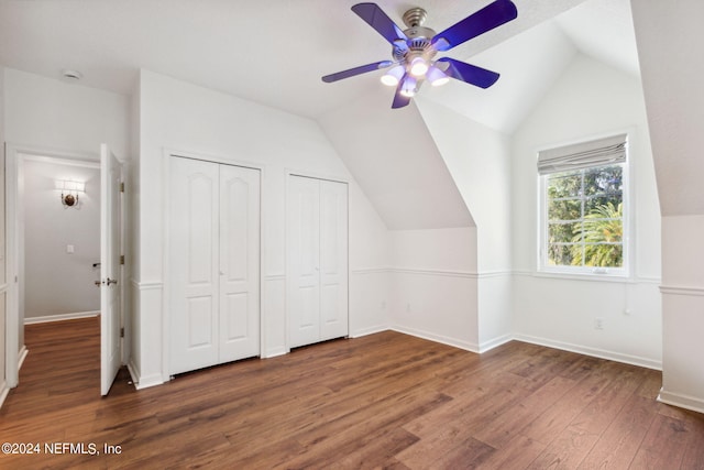 unfurnished bedroom featuring vaulted ceiling, ceiling fan, multiple closets, and dark wood-type flooring