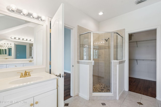 bathroom featuring oversized vanity, a shower with shower door, and tile flooring