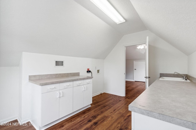 kitchen with white cabinets, dark hardwood / wood-style floors, sink, vaulted ceiling, and a textured ceiling