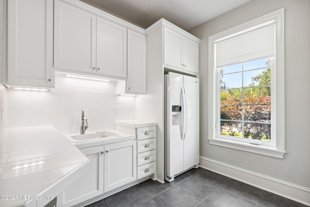 kitchen featuring a healthy amount of sunlight, white refrigerator with ice dispenser, tasteful backsplash, and sink