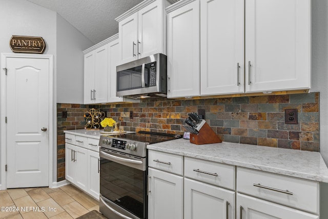 kitchen featuring light stone counters, appliances with stainless steel finishes, a textured ceiling, tasteful backsplash, and white cabinetry