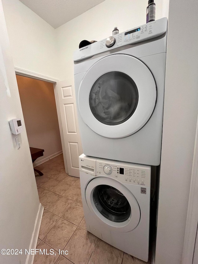 washroom with stacked washer and dryer and light tile patterned floors