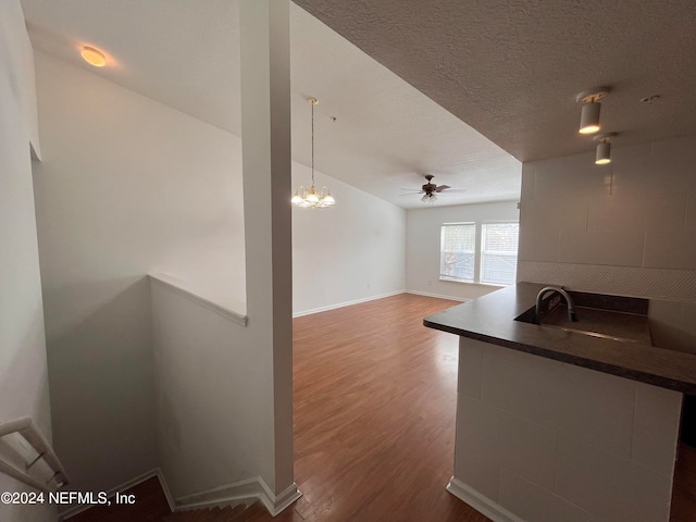 unfurnished living room featuring hardwood / wood-style floors, a textured ceiling, and ceiling fan with notable chandelier