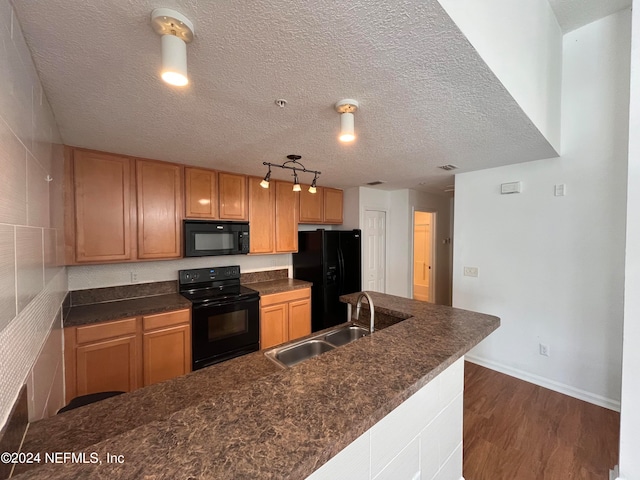 kitchen featuring sink, a textured ceiling, black appliances, and dark hardwood / wood-style flooring