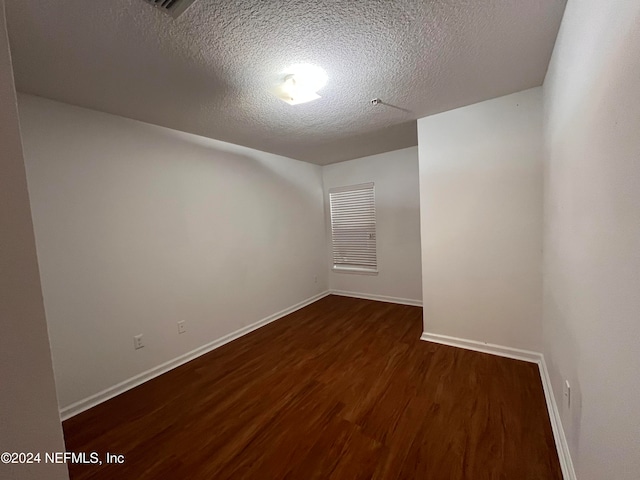 unfurnished room with a textured ceiling and dark hardwood / wood-style flooring