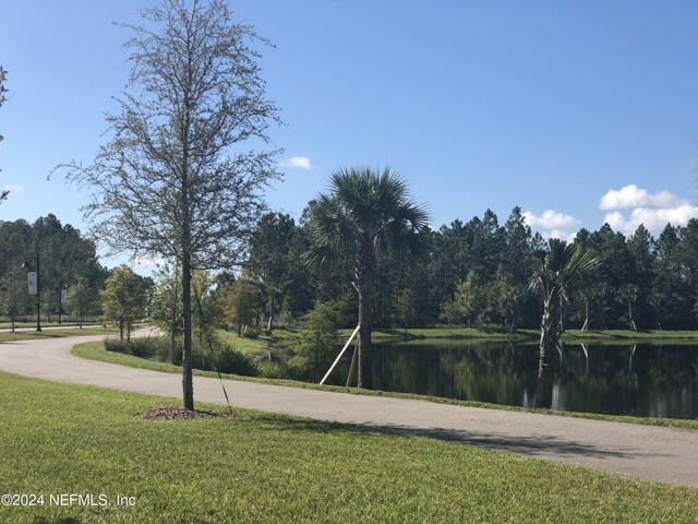 view of property's community with a lawn and a water view