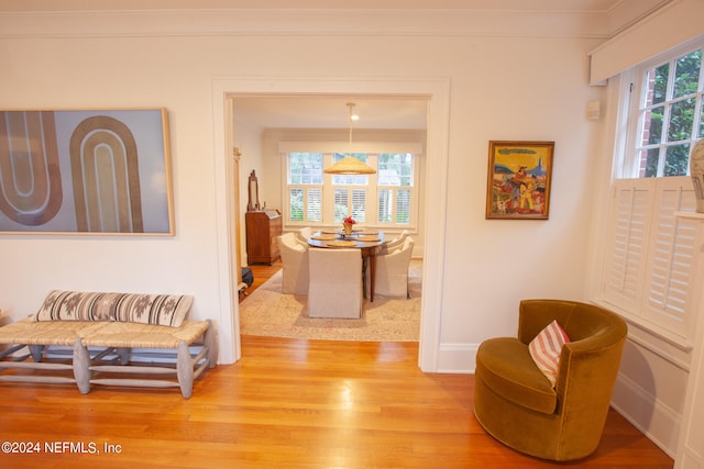 living area with crown molding and light wood-type flooring