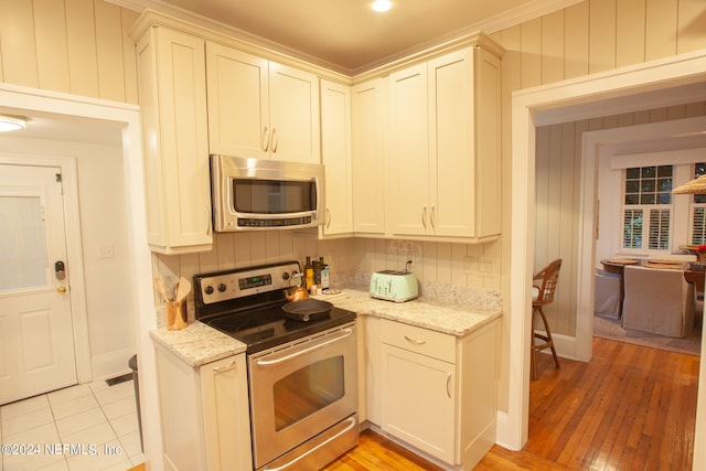 kitchen with appliances with stainless steel finishes, tasteful backsplash, light stone countertops, and white cabinetry