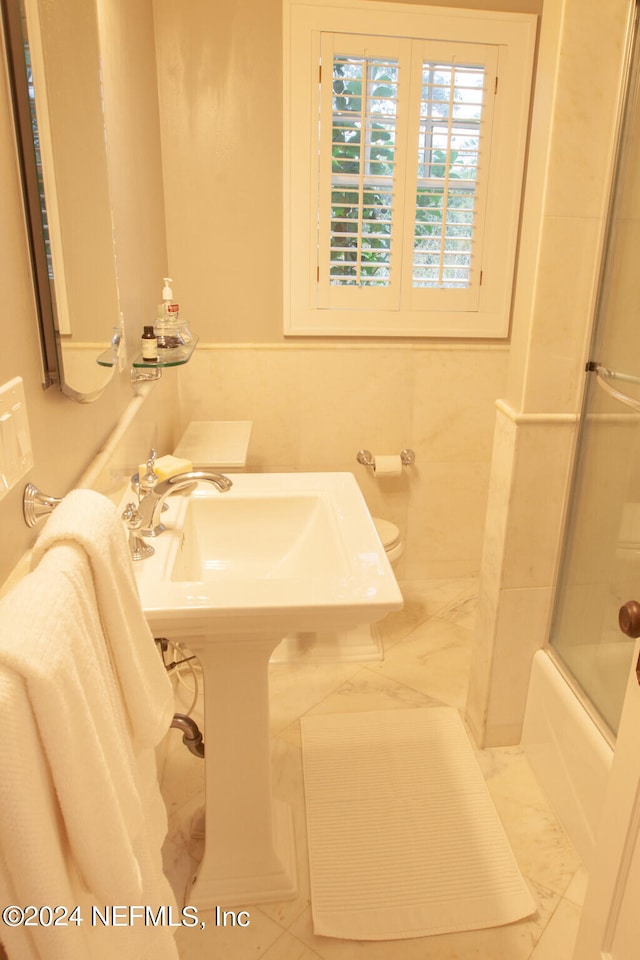 bathroom featuring toilet, enclosed tub / shower combo, and tile flooring