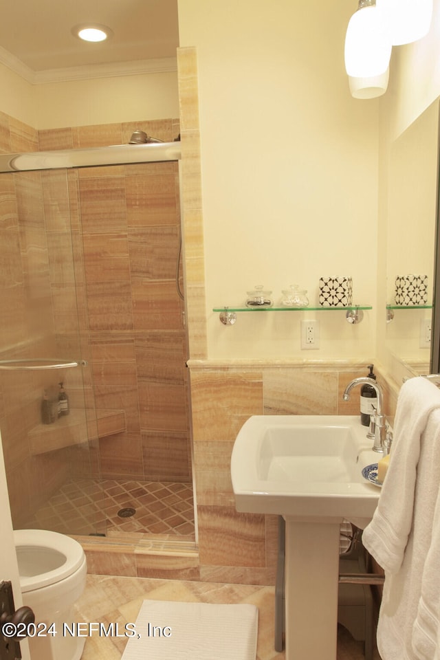 bathroom with ornamental molding, toilet, a tile shower, and tile flooring