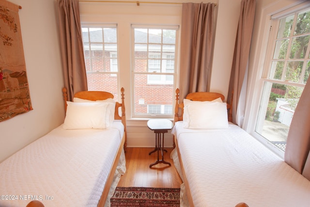 bedroom with wood-type flooring, access to outside, and multiple windows