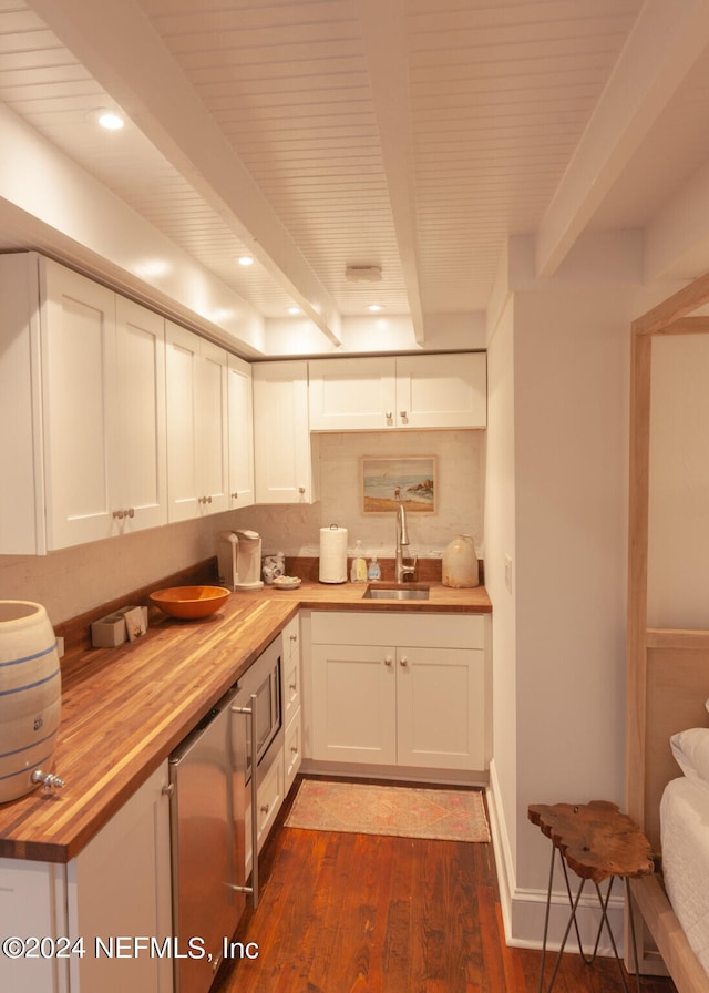 kitchen with beamed ceiling, wooden counters, sink, white cabinetry, and dark hardwood / wood-style flooring