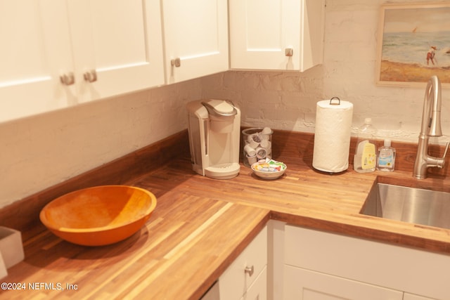 kitchen with butcher block countertops, sink, and white cabinetry