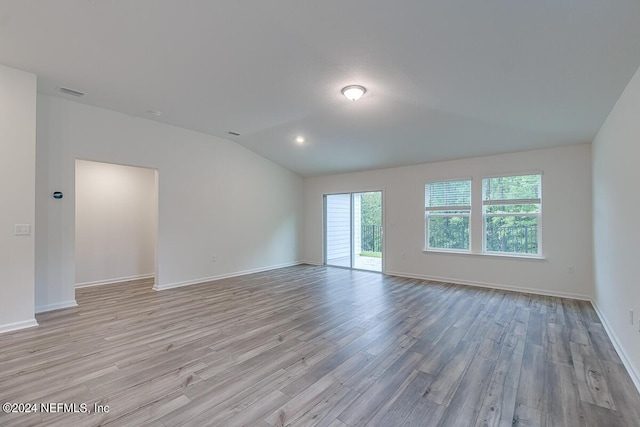 unfurnished room with vaulted ceiling and light wood-type flooring