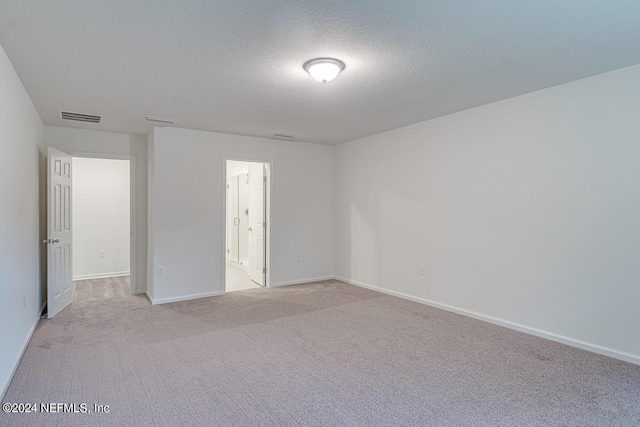 spare room with light carpet and a textured ceiling