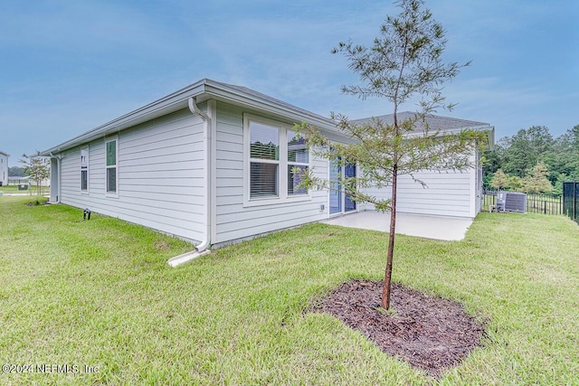 view of side of home featuring central AC unit, a patio area, and a yard