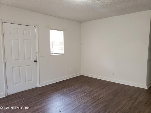 spare room featuring dark hardwood / wood-style floors and a textured ceiling