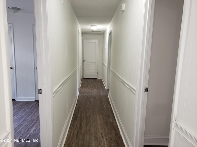 corridor featuring a textured ceiling and dark hardwood / wood-style flooring