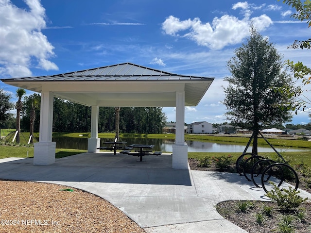 view of home's community with a gazebo, a water view, a patio, and a lawn