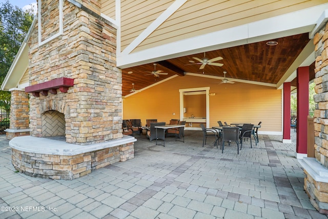 view of patio / terrace featuring ceiling fan, an outdoor stone fireplace, and outdoor dining space