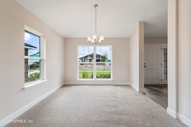 unfurnished dining area with carpet flooring and an inviting chandelier