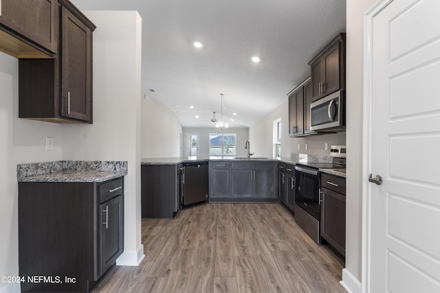 kitchen with lofted ceiling, appliances with stainless steel finishes, a sink, and dark brown cabinetry