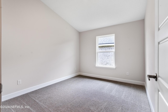 empty room with lofted ceiling, carpet, and baseboards