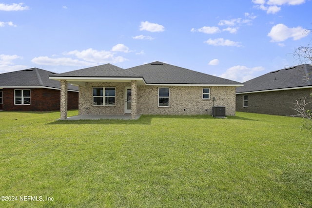 back of property featuring brick siding, a patio, a shingled roof, a lawn, and central AC