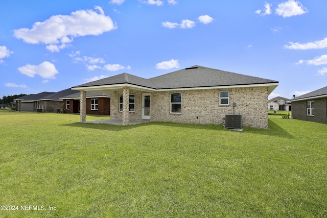 rear view of property featuring brick siding, a yard, a patio, and central AC unit