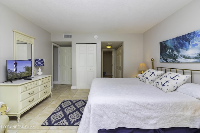 bedroom featuring light tile patterned floors, baseboards, visible vents, and a closet