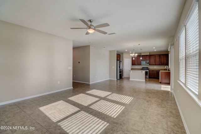 unfurnished living room featuring ceiling fan with notable chandelier, sink, and light tile floors