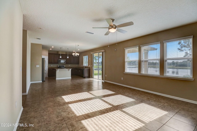 unfurnished living room featuring ceiling fan with notable chandelier, tile floors, and a textured ceiling