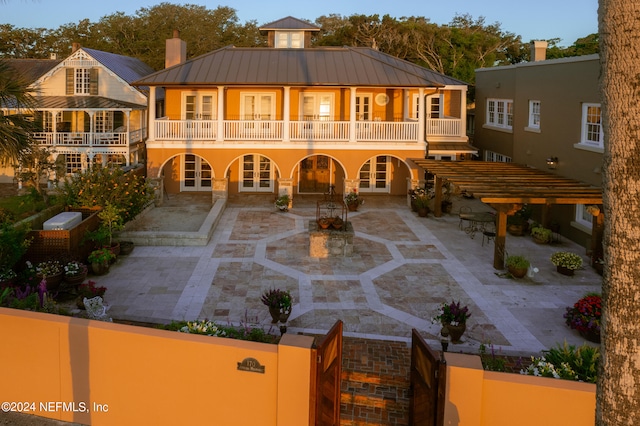 view of front of property with french doors, a balcony, and a patio