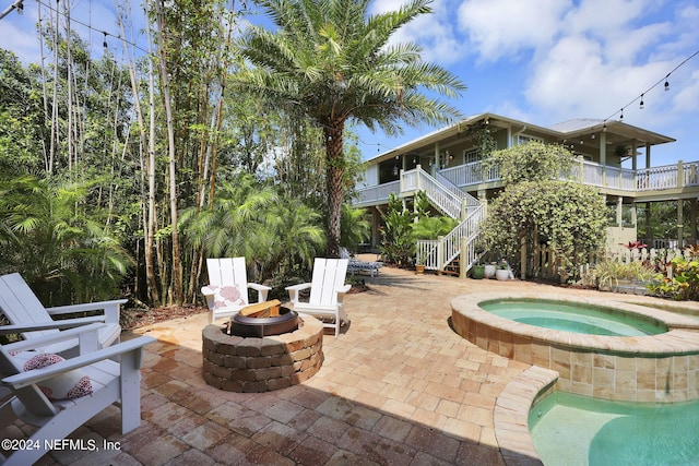 view of swimming pool with stairs, an in ground hot tub, a patio area, and an outdoor fire pit