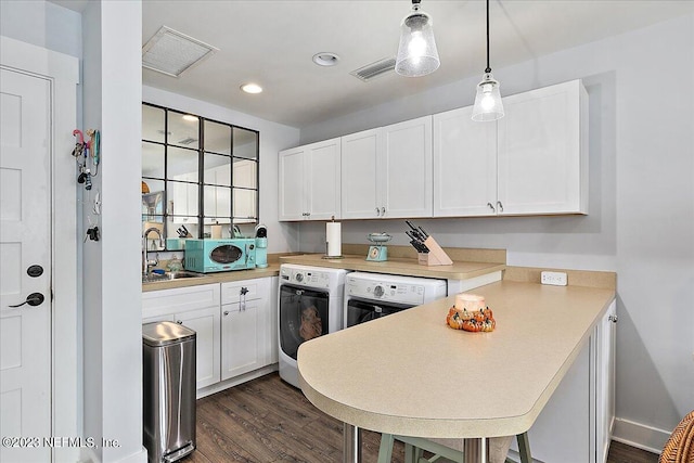 kitchen featuring sink, dark wood-type flooring, washer and dryer, and white cabinetry