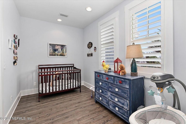 bedroom featuring wood-type flooring and a crib