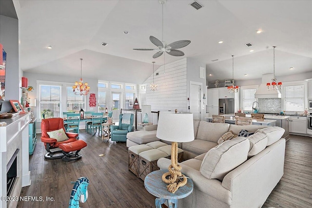 living room with high vaulted ceiling, ceiling fan with notable chandelier, and dark wood-type flooring