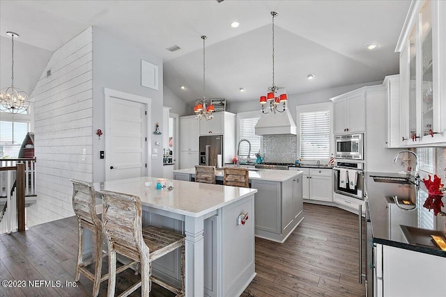 kitchen featuring built in appliances, premium range hood, hanging light fixtures, dark wood-type flooring, and a kitchen island