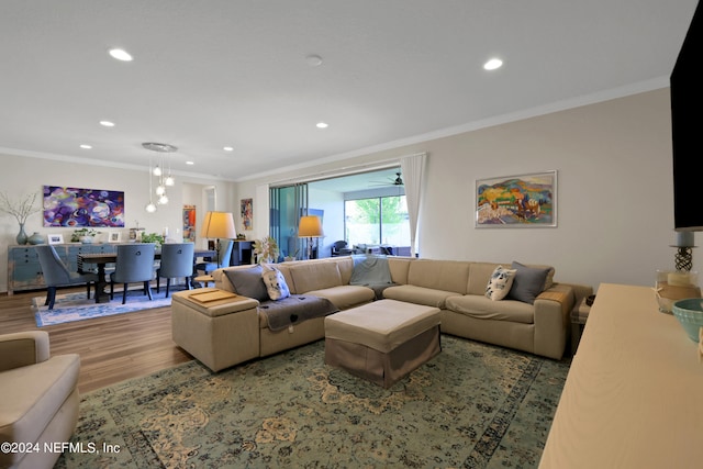 living room with hardwood / wood-style flooring, crown molding, and ceiling fan